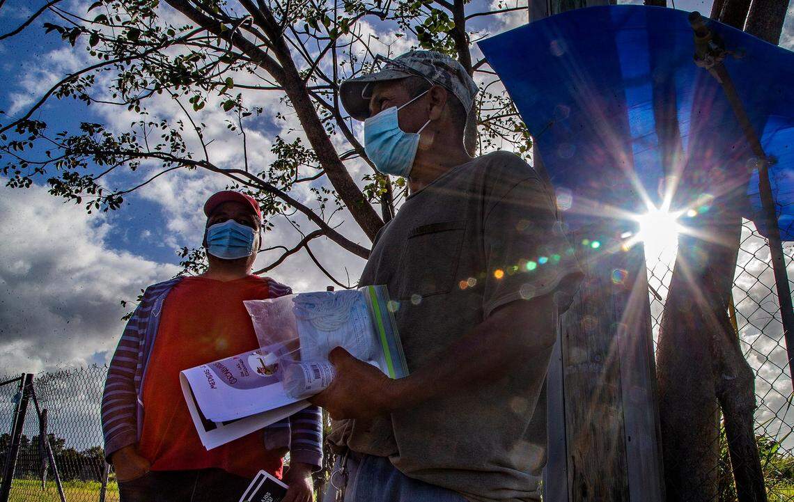 José Alfredo (right), a laborer, holds a flyer with information about workers’ rights and a kit including COVID protection guidance from the CDC, masks and hand sanitizer.