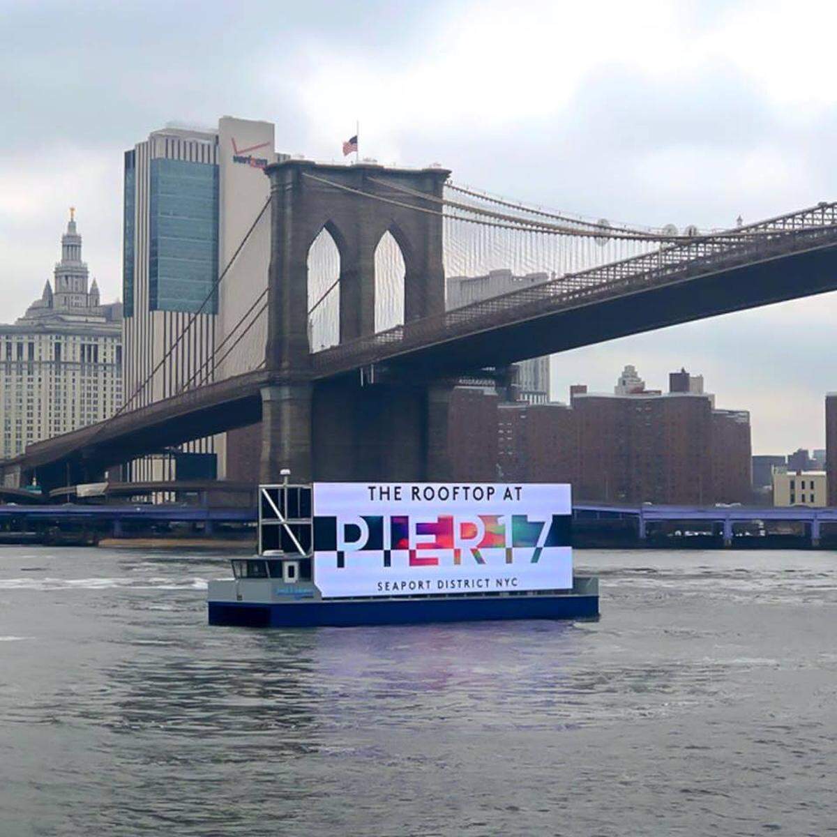 A Ballyhoo Media barge displays a billboard near the Brooklyn Bridge.