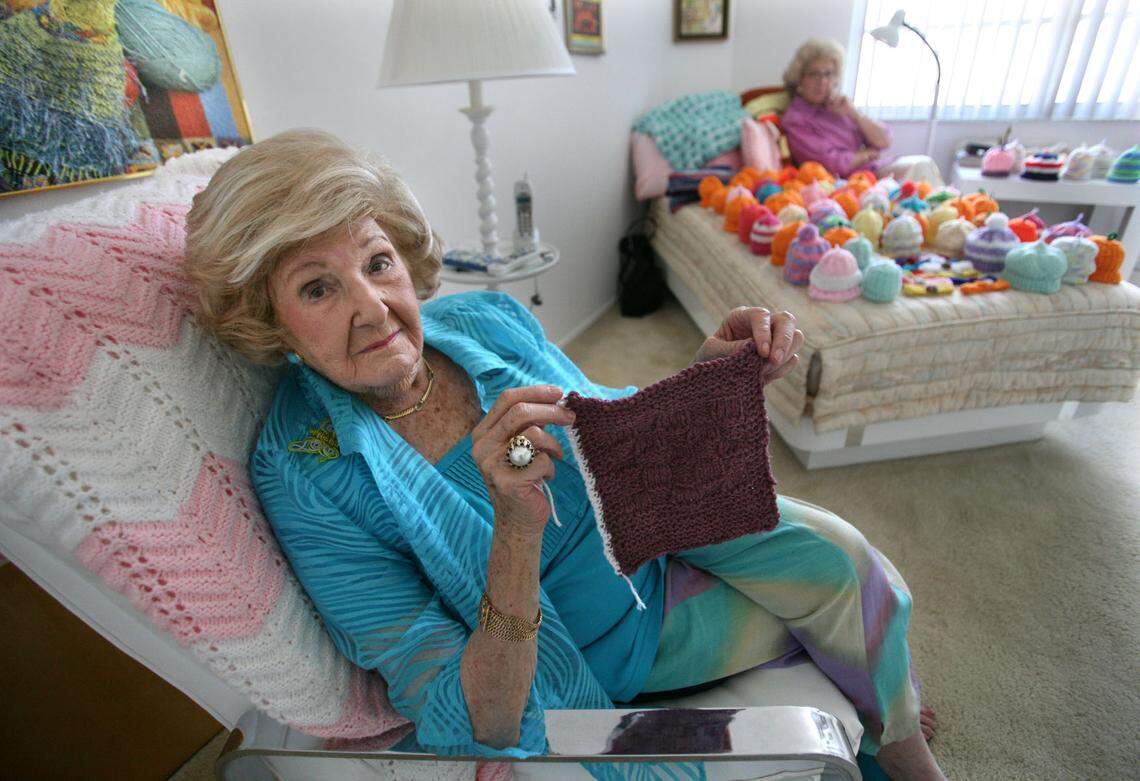 In this Oct. 7, 2008, file photo Mazie Ford, then-102, of Hallandale Beach, and her daughter Johann Levinson, then-80, of Pompano, knitted hundreds of caps, blankets and head bands for newborn and sick babies at Joe DiMaggio Children’s Hospital in Hollywood. Here, in the guest room where Ford enjoyed watching television while she knit nearly every night, Ford showed a square she knitted long ago that started her philanthropic hobby.