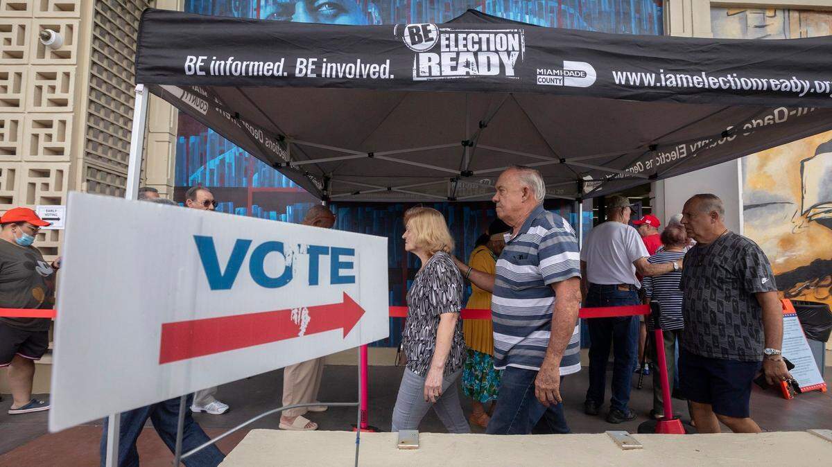 People stand in line to vote during the first day of in-person early voting for the 2024 election at the John F. Kennedy Library on Monday, Oct. 21, 2024 in Hialeah, Florida.