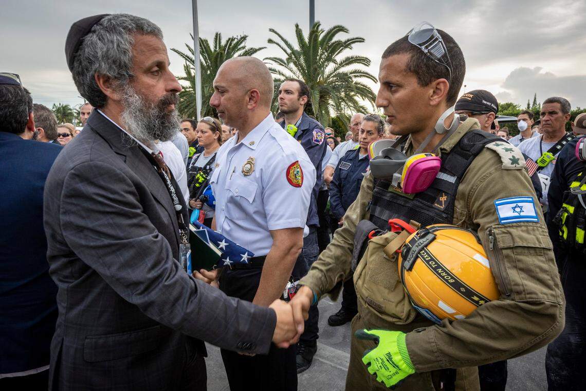 Police Chaplain and Rabbi Youssef Harlig, left, shakes hands with Col. Elad Edri of the Israeli defense forces search and rescue team on July 7 in Surfside. Members of search-and-rescue teams and Miami-Dade Fire rescue along with police and workers who have been working at the site gathered for a moment of prayer and silence next to the collapsed tower.