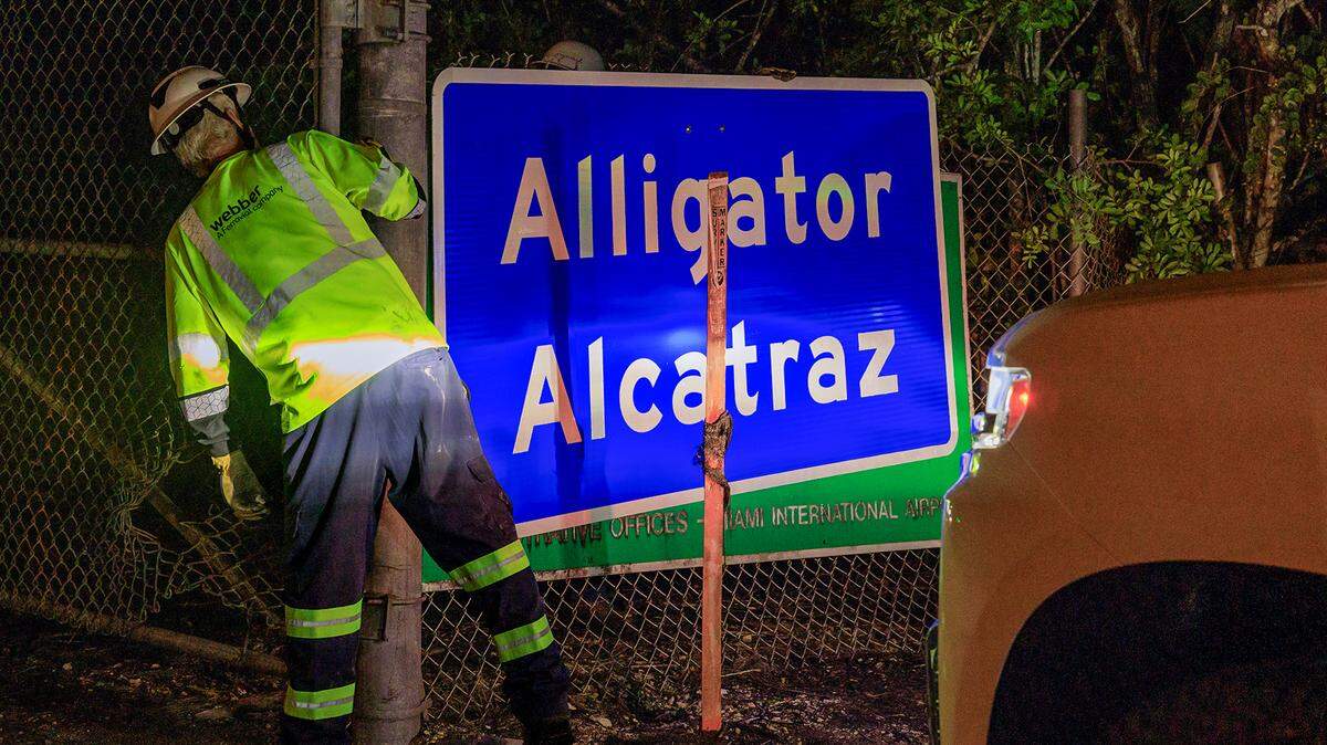 Two workers finished covering the Dade-Collier Training and Transition Airport with the “Alligator Alcatraz,” sign at the entrance of the migrant detention center, in Ochopee, Florida on Wednesday July 02, 2025.