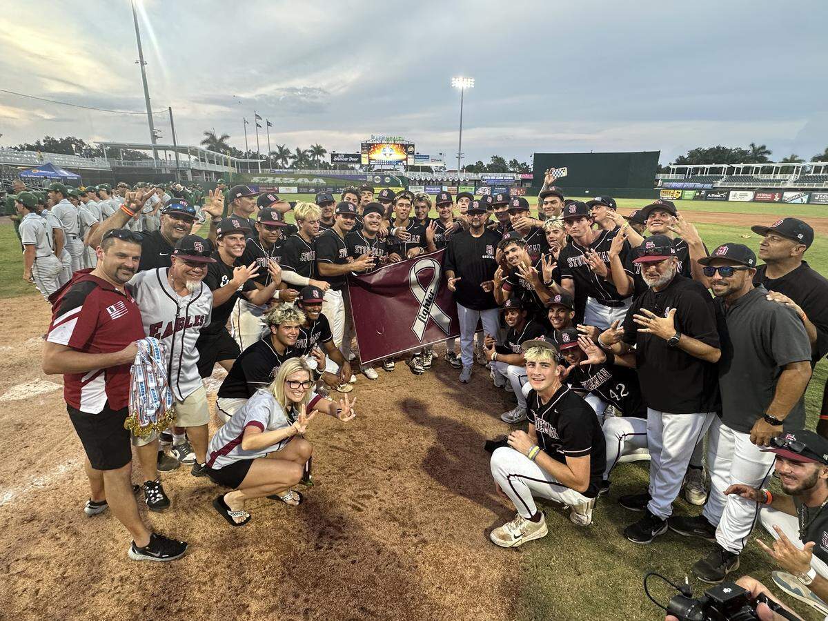 The Stoneman Douglas baseball team holds a banner with the word “Fighter” in tribute in honor of members of the team’s families who are battling cancer after Saturday’s Class 7A state baseball championship game in Fort Myers, Fla.