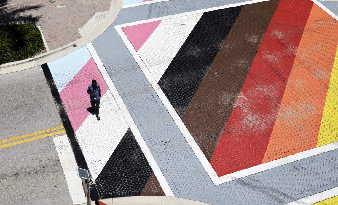 A pedestrian crosses the LGBTQ+ pride intersection of Northeast First Street and Northeast Second Avenue in Delray Beach on Monday, Aug. 18, 2025. On Friday, the southeast Florida district secretary of the state Department of Transportation ordered City Manager Terrence Moore to have the intersection removed by Sept. 3. (Carline Jean/South Florida Sun Sentinel)