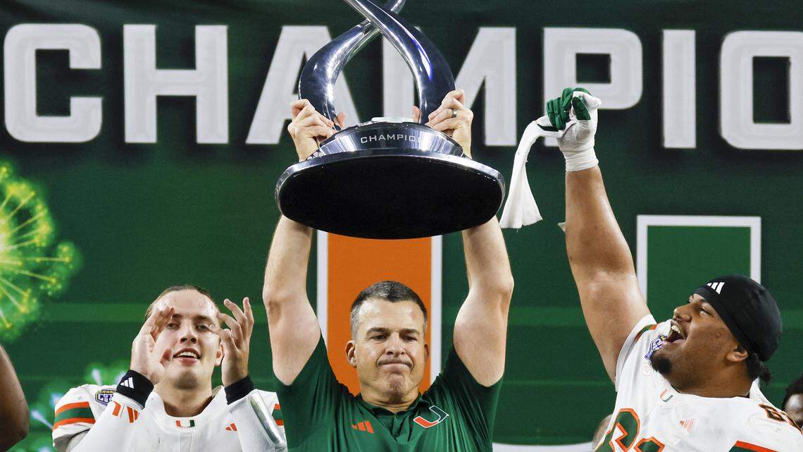 Miami Hurricanes quarterback Carson Beck (11) and offensive lineman Francis Mauigoa (61) reacts as head coach Mario Cristobal lifts the Cotton Bowl Championship Trophy after winning the College Football Playoff quarterfinal game against the Ohio State Buckeyes at AT&T Stadium in Arlington, Texas on Wednesday, December 31, 2025.