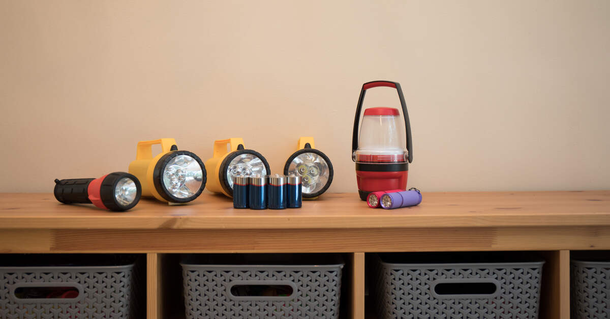 Flashlights and batteries laid out on a table prepared for a power outage.