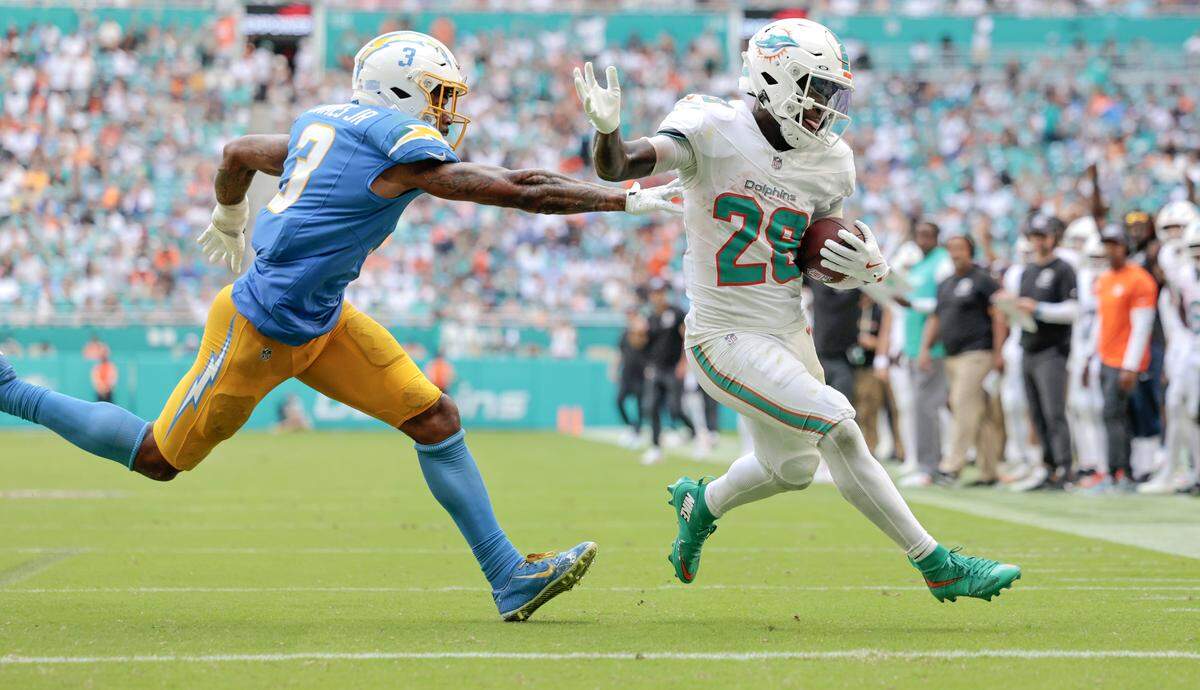 Miami Dolphins running back De'Von Achane (28) scores as Los Angeles Chargers free safety Derwin James (3) gives chase during the second half of their NFL football game at Hard Rock Stadium in Miami Gardens, FL, on Sunday, October 12, 2025. 