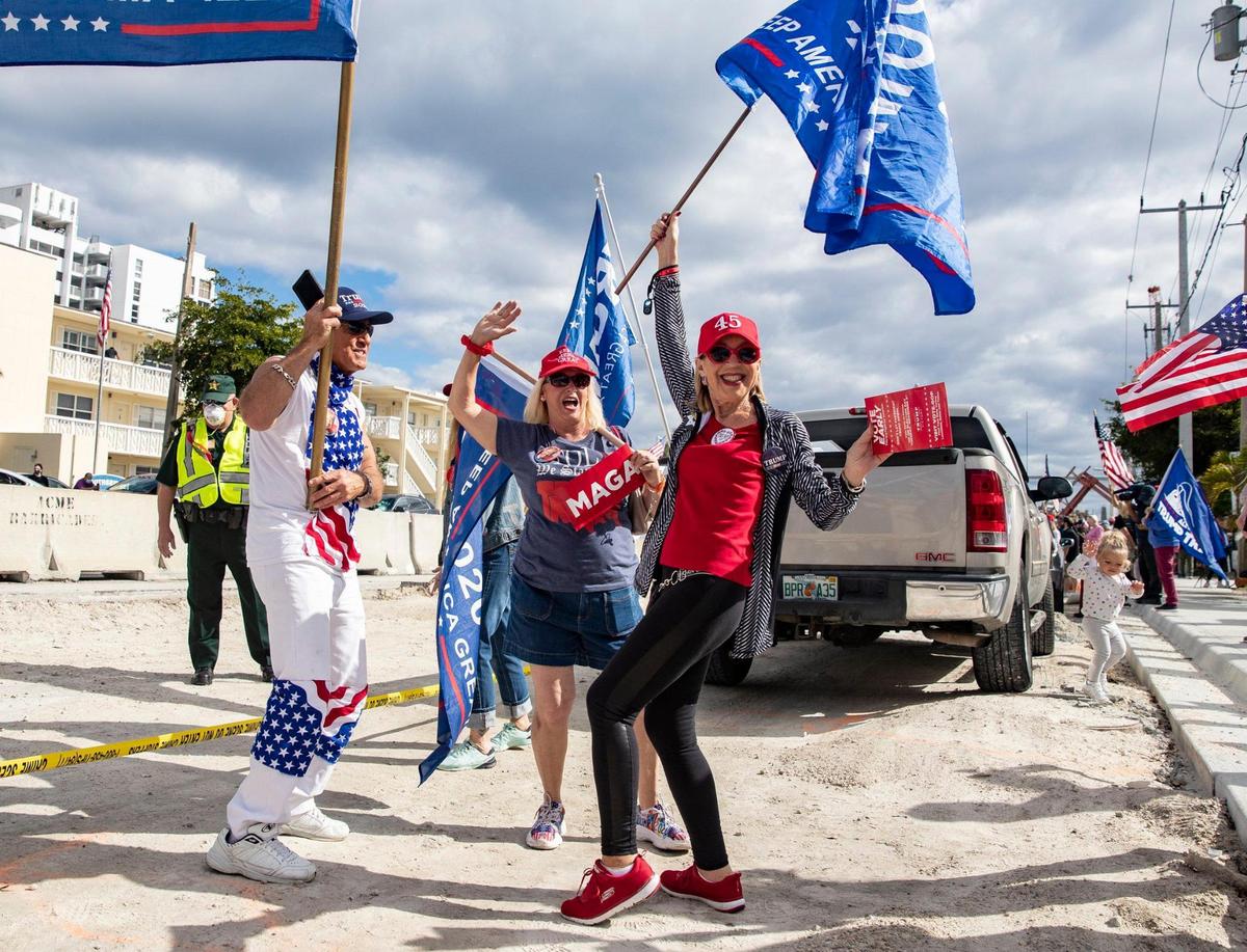Brett Brown (izq) y Gloria Birmbaum (derecha), partidarios de Trump, esperan la llegada de su caravana en Southern Boulevard, en dirección a Mar-a Lago en Palm Beach, el miércoles 20 de enero de 2021..