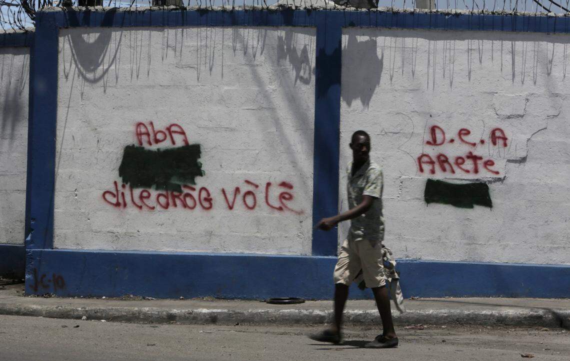 In this file photo, a man walks past the government port in Port-au-Prince, Haiti, where graffiti on the walls calls for the DEA to arrest someone for drug dealing.