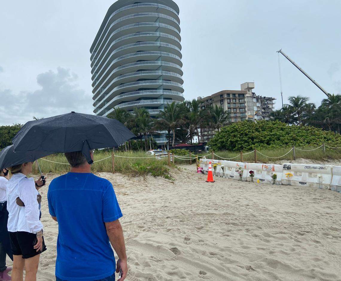 Shan and David Luvista, stand on the beach in Surfside Wednesday, June 30, 2021, to see wreckage of the Champlain Towers South building.