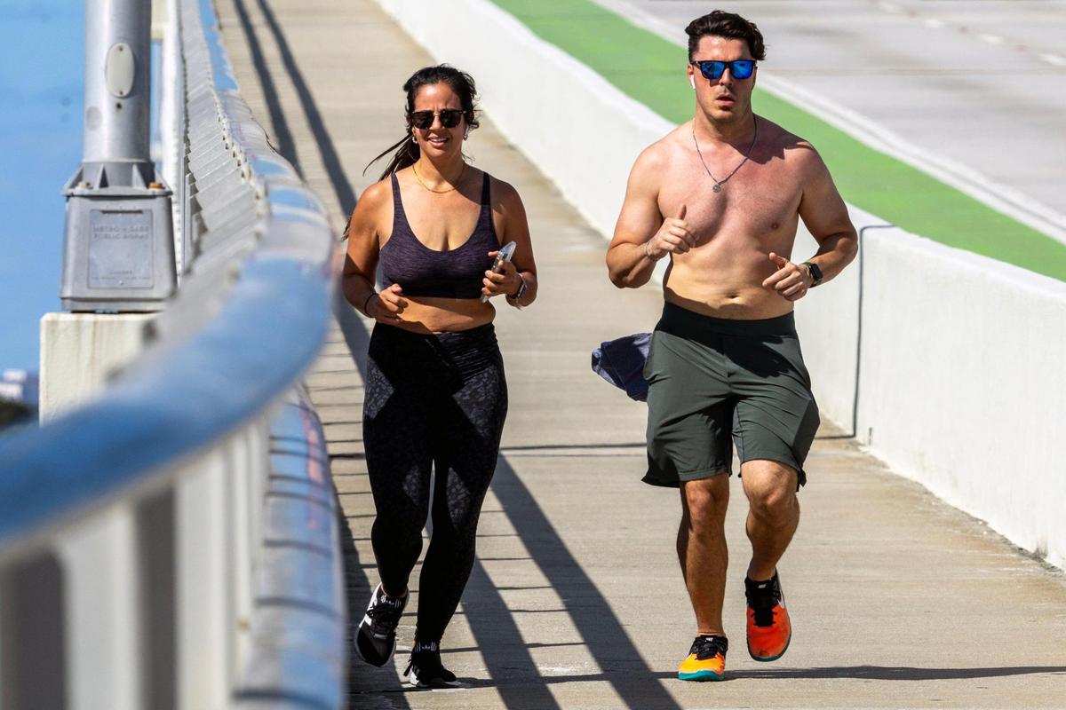 Josie Ferrer, 36, and David Alvarez, 37, jog down the William M. Powell Bridge on the Rickenbacker Causeway in Miami, Florida, on Wednesday, Feb. 22, 2023. Temperatures are soaring to the mid- to upper-80s on Wednesday and the rest of the week.