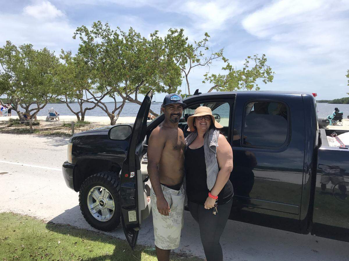 Harry Lopez and Melissa McGuire stand by their pickup truck Monday, June 1, 2020, at the beach at John Pennekamp Coral Reef State Park in Key Largo. The couple is vacationing from Orlando.