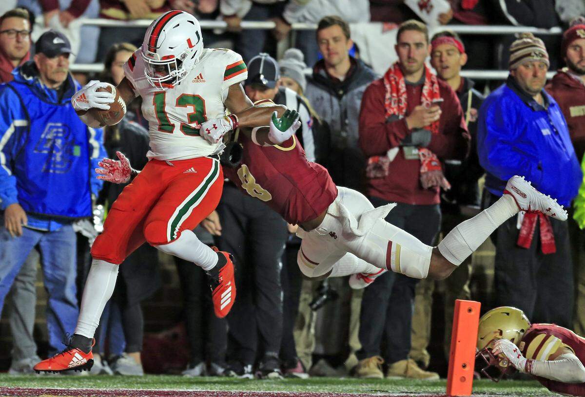 Miami Hurricanes running back DeeJay Dallas (13) scores in the second quarter as Boston College Eagles defensive back Will Harris (8) defends as the University of Miami plays Boston College at Alumni Stadium in Chestnut Hill on Friday, October 26, 2018.