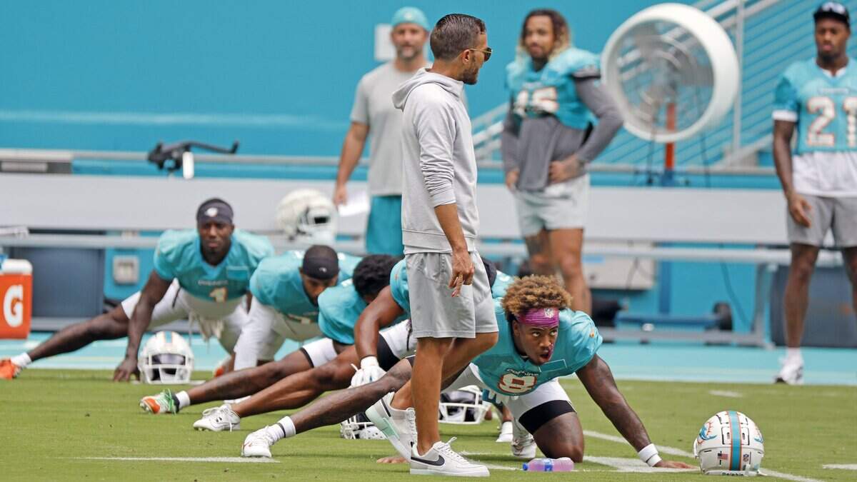 Miami Dolphins coach Mike McDaniel walks past safety Jevon Holland (8) during stretches at a team scrimmage at Hard Rock Stadium in Miami Gardens on Saturday, August 5, 2023.