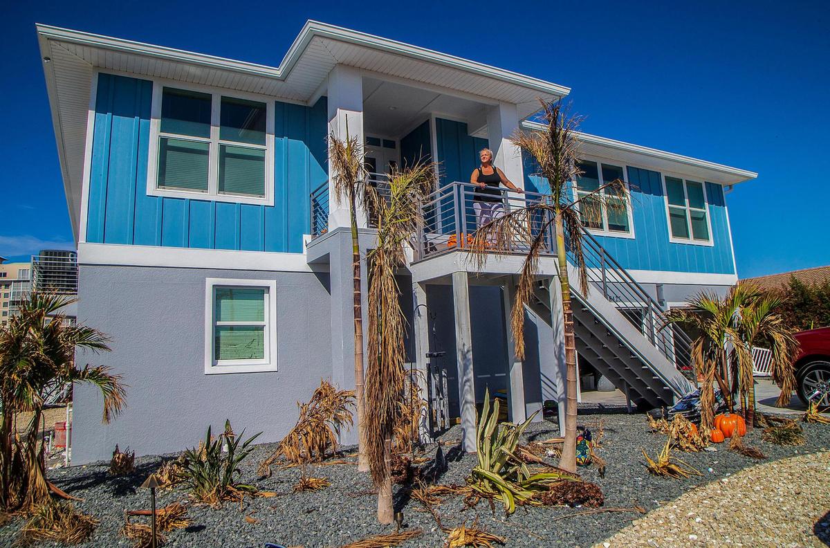 Amy Rizzo stands by the entrance of her Lagoon Road stilted house Wednesday, Oct. 26, 2022. She and her husband stayed in the house when Hurricane Ian made landfall in the area Wednesday, Sept. 28, 2022. 
