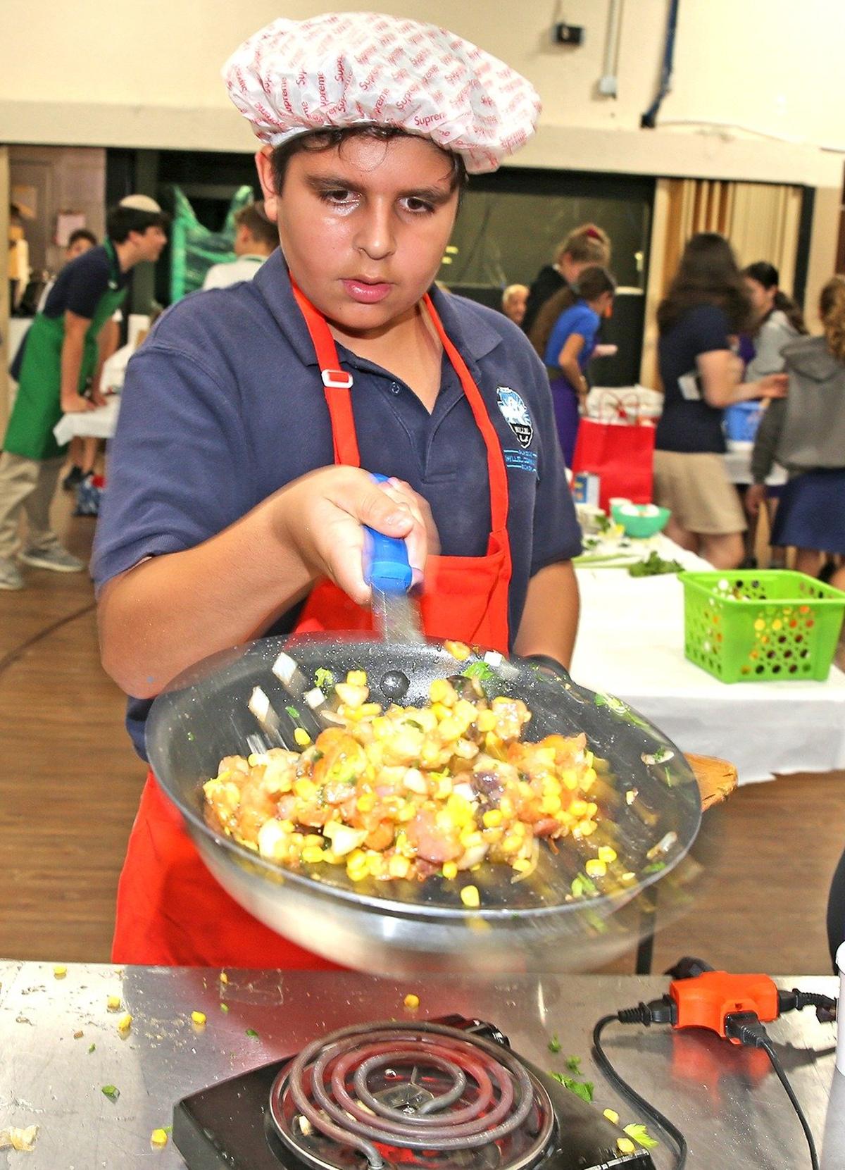 Eyal Vaxman, 13, stirs his ingredients as he and his team prepare food in a cooking contest at Scheck Hillel Community School in North Miami Beach.