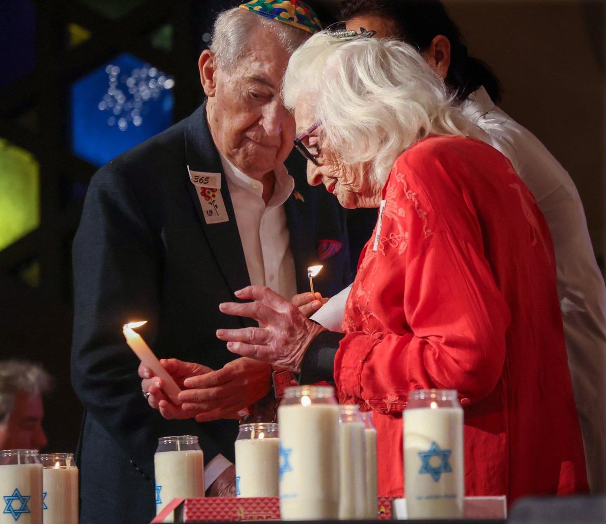 Holocaust survivors David Schechter, left, and Dr. Miriam Klein Kassenoff, right, light candles during the moment of silence and memorial candle lighting for victims of the October 7 massacre. Greater Miami Jewish community gathered at Temple Beth Sholom in remembrance of those who were killed in the attack.