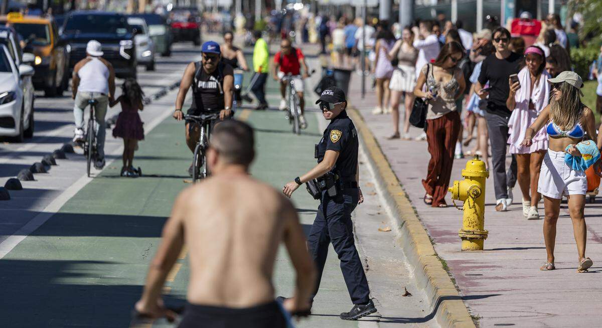 A Miami Beach police officer looks on as people make their way down Ocean Drive during spring break on Saturday, March 21, 2026, in Miami Beach, Fla.