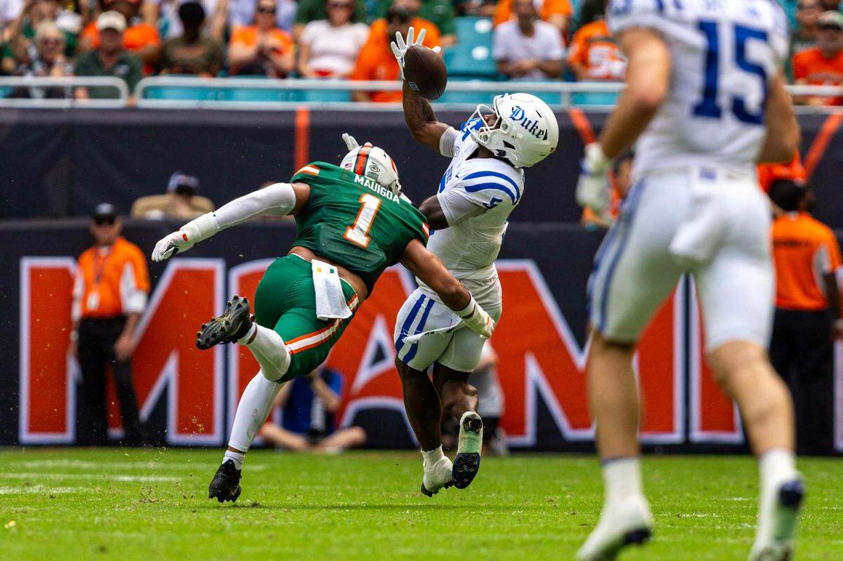 Duke Blue Devils running back Peyton Jones (5) makes a catch while defended by Miami Hurricanes linebacker Francisco Mauigoa (1) during the first half of an ACC football game at Hard Rock Stadium on Saturday, Nov. 2, 2024, in Miami Gardens, Fla.