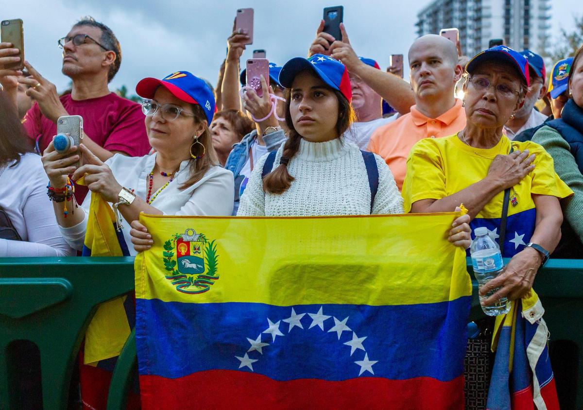 Claudia Kahwati, 18, center, holds a Venezuelan flag during a protest in Downtown Doral Park on Wednesday, Jan. 23, 2019. Thousands of activists gathered in Doral in support of Juan Guaidó, the president of Venezuela’s National Assembly who declared himself the country’s interim president.