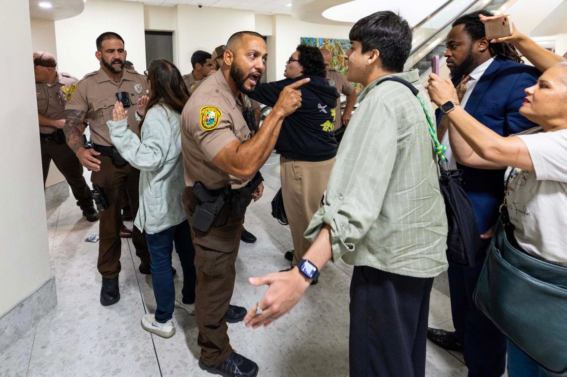 Miami-Dade officer D. Carrero warns a member of the public to stand back during a Miami-Dade County Commission meeting at the Stephen P. Clark Government Center on Thursday, June 26, 2025, in Miami.