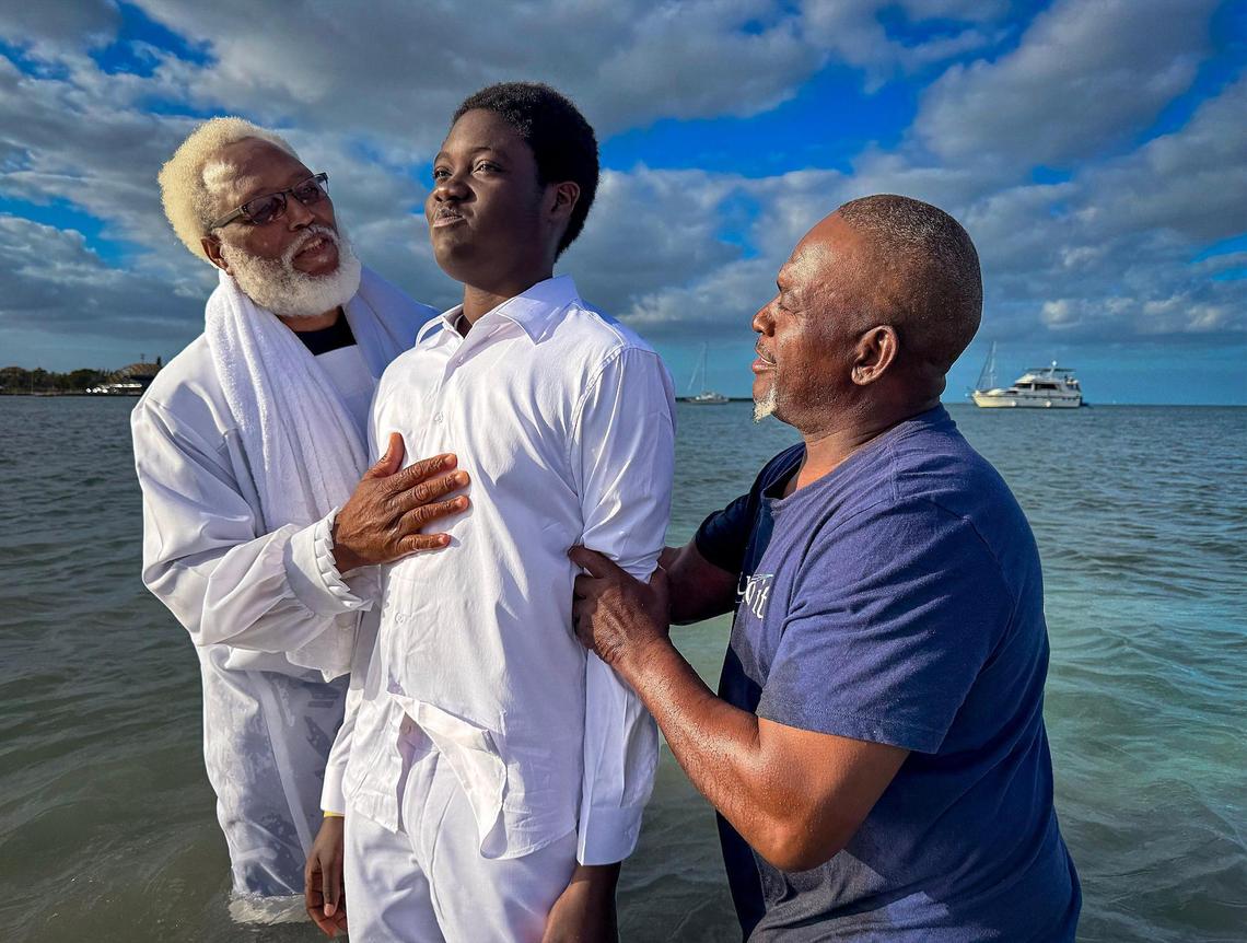 Ansglory Desir, center, member of the Jesus Christ True Church prepares to being submerged underwater by Minister Allen Mushgrove, left, and Apostle Leon Everett, right, during his baptism.