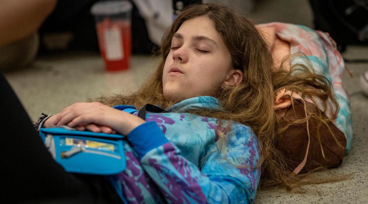 Miami, Florida - June 20, 2023 - Student Michelle McMullen takes a nap while she and her fellow students wait for a flight to Costa Rica. A group of Middle school students from Reno, Nevada missed their connection to Costa Rica last night after their flight to Miami was diverted to Tampa due to thunderstorms.