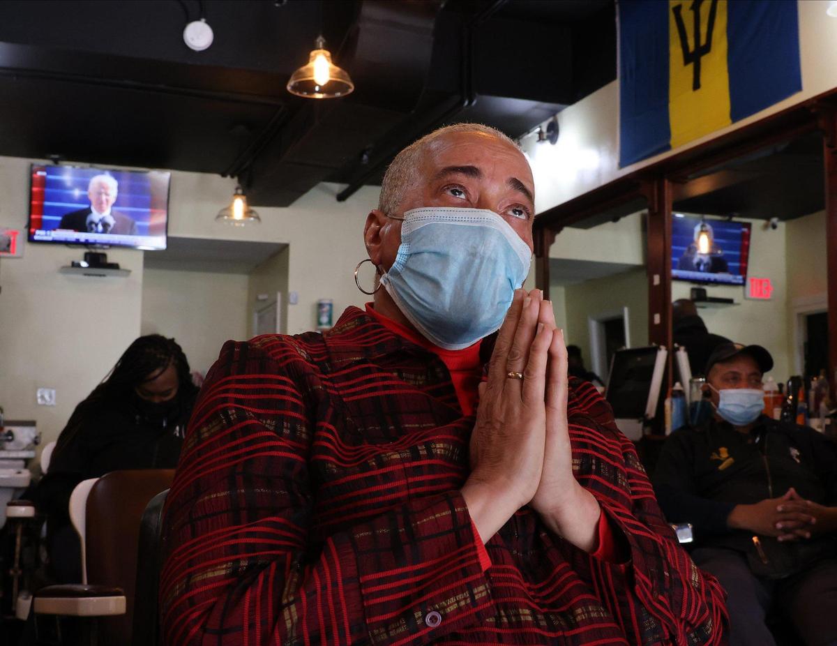 June Everett clasps her hands in prayer while listen to President Joe Biden’s speech as she sit glued to the flat screen during the telecast of the Inauguration. On Wednesday, January 20, 2021 Barbados-born barber shop owner June Everett watches along with customers and employees the Inauguration of President-elect Joe Biden and Vice President-elect Kamala Harris as the nation’s first Hispanic Supreme Court justice, Sonia Sotomayor swears in the first African-American woman of Caribbean and East Asian descent as vice president of the United States. Everett barber shop is in the heart of the U street just few block alway from HBCU, Howard University, where Vice-President Kamala Harris went to college.