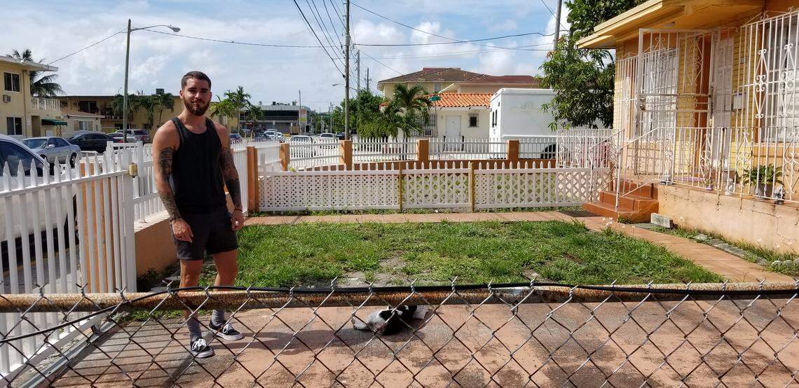 Reiner Toledo stands outside the two-bedroom home he shares with his brother in Flagami on July 3, 2019, as his pet French bulldog, Jazz, takes in some sun.