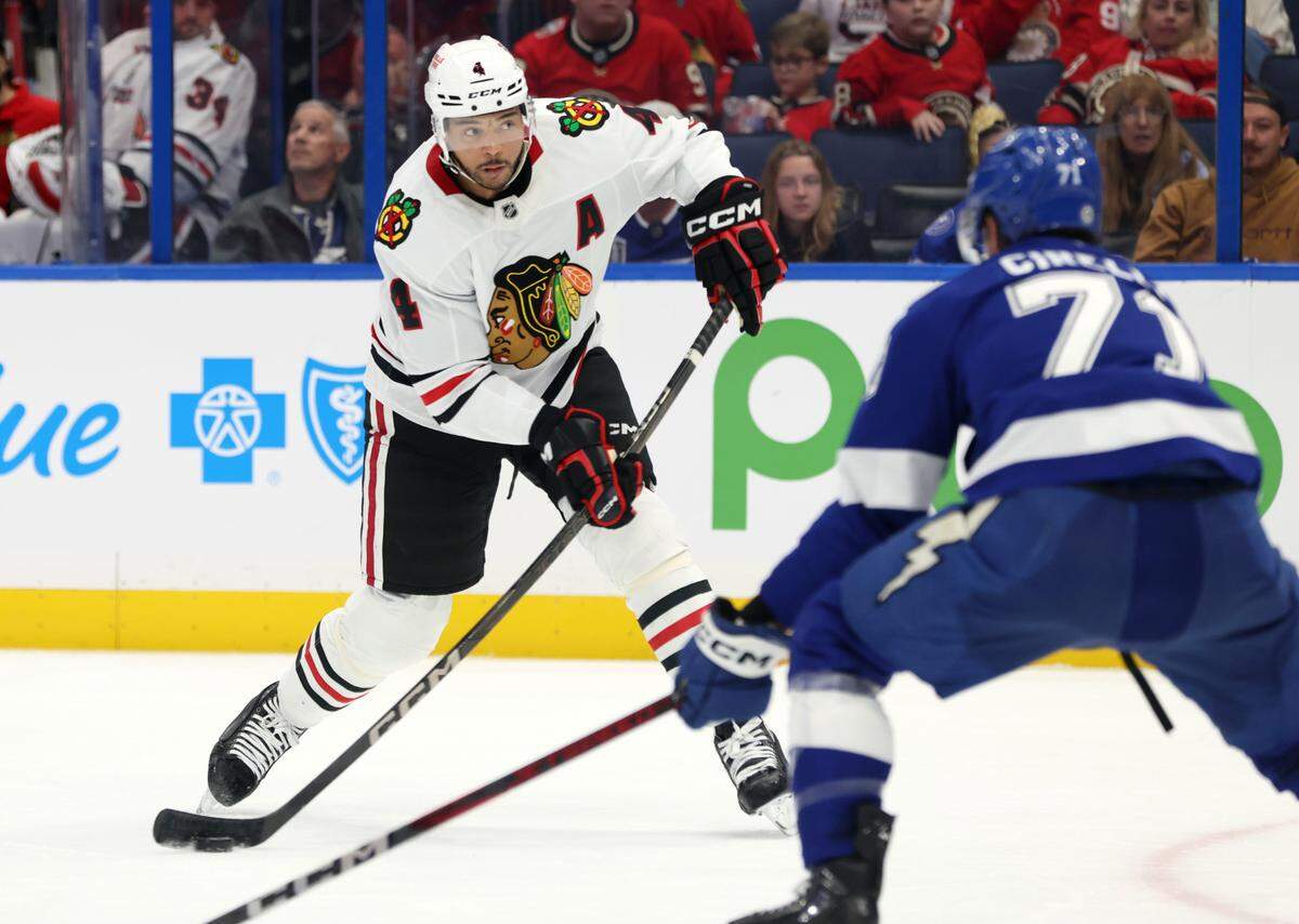 Jan 28, 2025; Tampa, Florida, USA; Chicago Blackhawks defenseman Seth Jones (4) shoots as Tampa Bay Lightning center Anthony Cirelli (71) defends during the second period at Amalie Arena. Mandatory Credit: Kim Klement Neitzel-Imagn Images