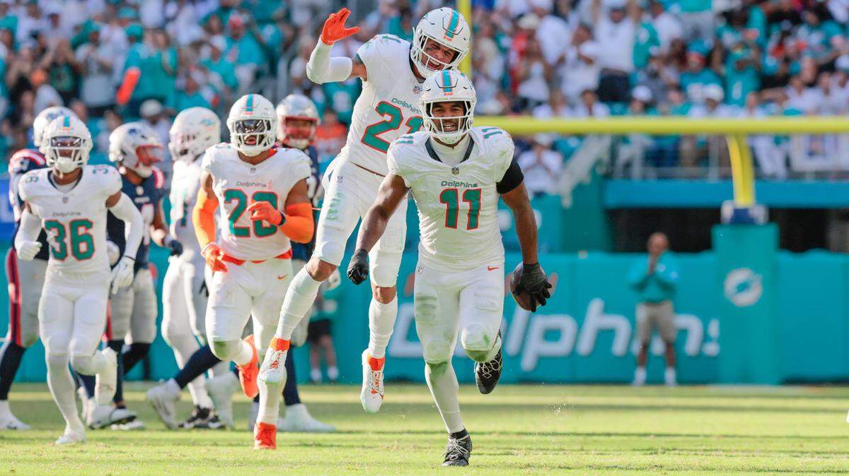Miami Dolphins linebacker Tyrel Dodson (11) and Miami Dolphins safety Jordan Poyer (21) celebrates after intercepting the ball in the second half against the New England Patriots during their NFL football game at Hard Rock Stadium in Miami Gardens, Florida, on Sunday, November 24, 2024.