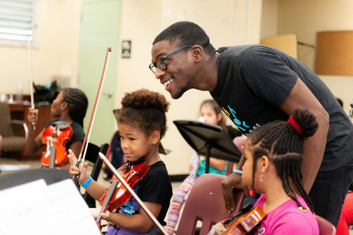 Bobby Bush, a teaching artist with the Miami Music Project, mentors a student on violin.