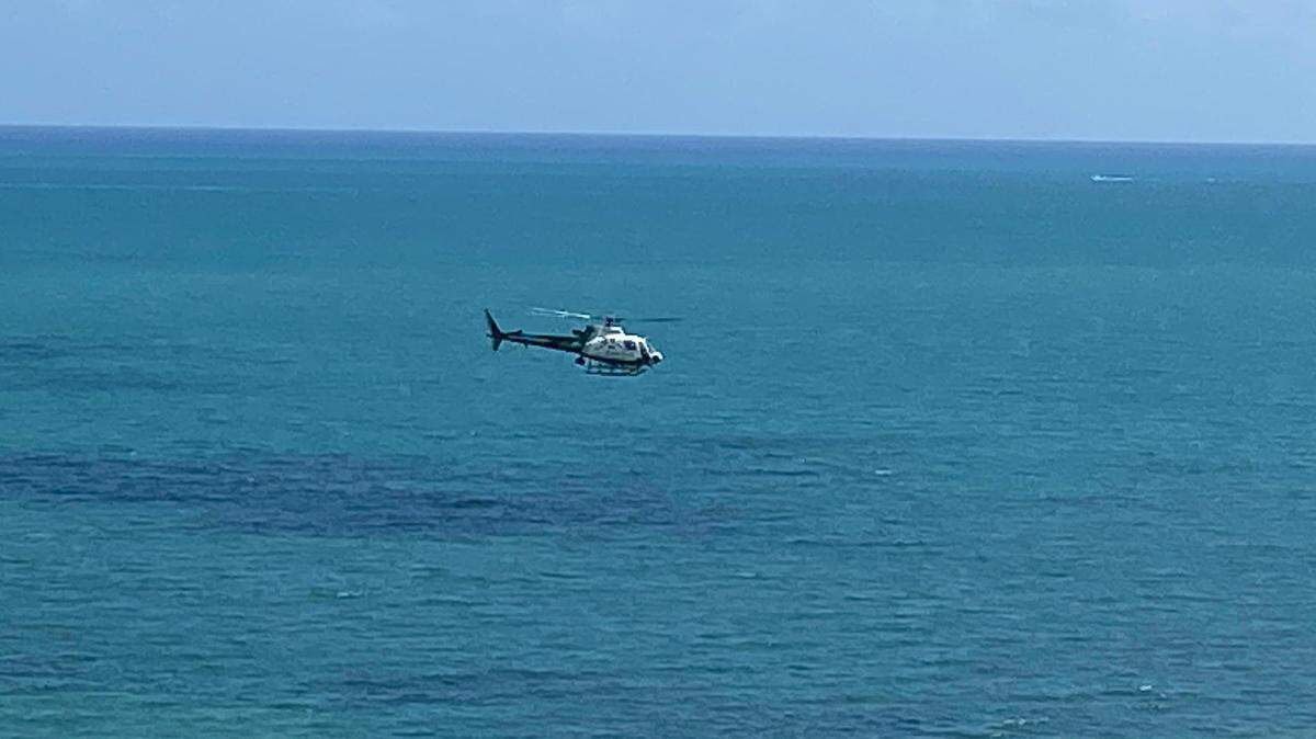 A Miami-Dade County Police helicopter flies low along the beach in Key Biscayne Monday, Feb. 21, 2022. A boater was reported missing in nearby Fisher Island.