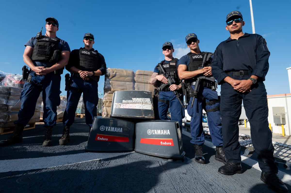 Law enforcement crew members from U.S. Coast Guard Cutter Valiant stand in front of seized cocaine and engine covers at Base Miami Beach Thursday, Mar. 6, 2025. The Valiant’s crew secured the illegal drugs after six interdictions in the international waters of the Caribbean.
