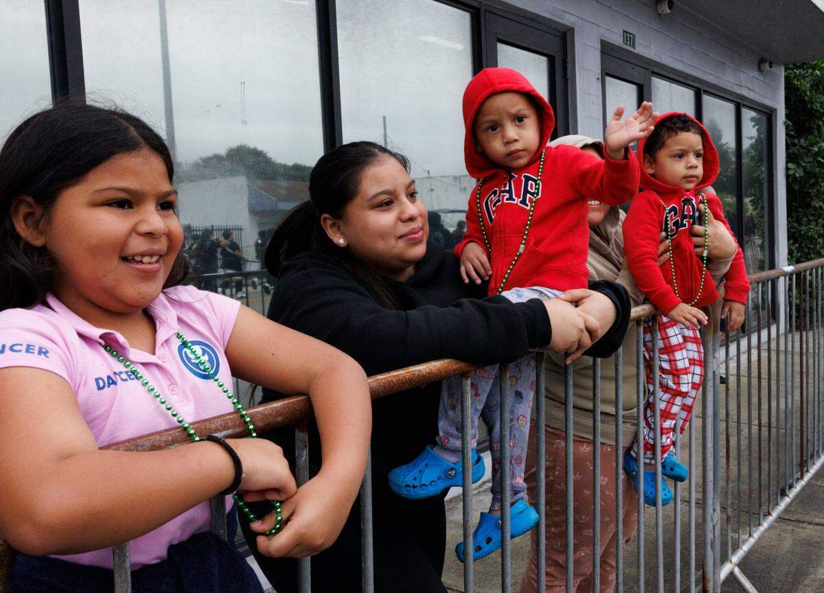 Jackson, center, and his twin, Jason, right, watch the Dr. Martin Luther King Jr. Day parade with their family on Monday, Jan. 20, 2025, in Liberty City in Miami, Fla. “I love seeing all the bands together; it’s a rainy day but everyone’s out enjoying,” said Diana Martinez.