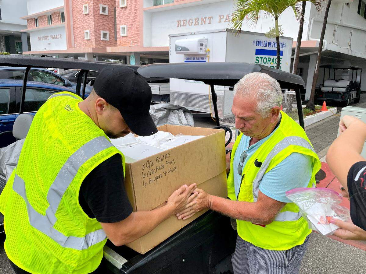 Yoni Maimon, left, and Jacob Ruben, volunteers at the kosher kitchen at the Surfside Community Center, load 200 meals in golf carts for delivery to families of those missing in the Champlain Towers collapse, staying in a nearby hotel.