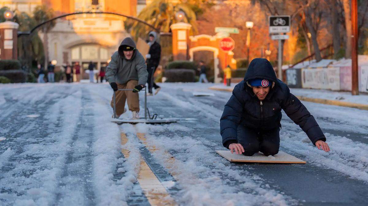 Matt Ramos, right, and Aaron Litavsky sled down College Avenue in front of Westcott Fountain, Wednesday, Jan. 22, 2025.
