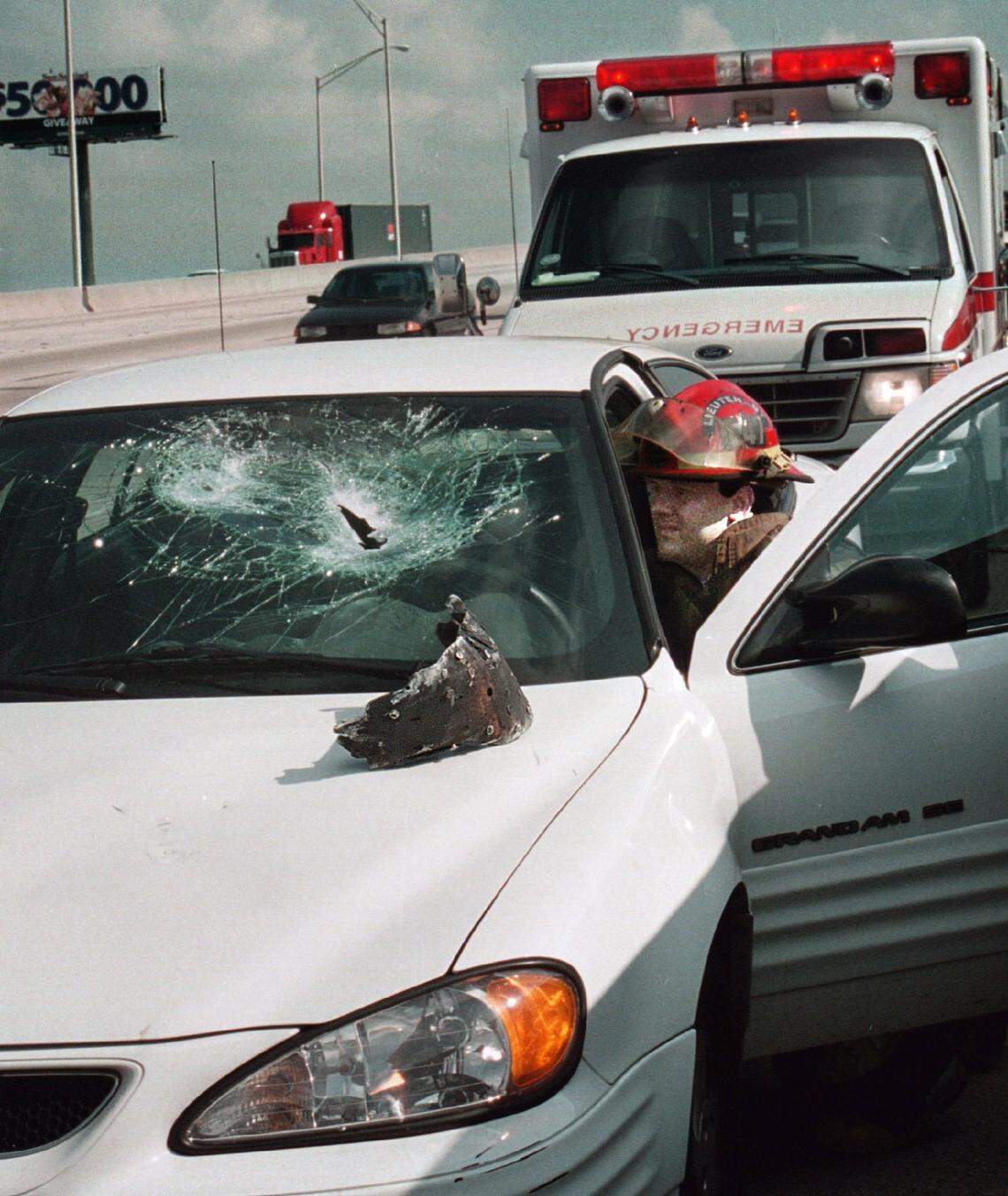 Broward 5-26-2000 Stephen R. McInerny Fort Lauderdale-Fire Rescue Lt. William Humphrey of Fort Lauderdale Fire Rescue Engine Co. 47 checks out damage to 1997 Pontiac Grand Prix driven by Ali Yasmin, 23, of Coral Springs. Car was hit in the windshield by a chunk of metal from the brake assembly of a semi-trailer truck. She was cut by flying glass. This was on southbound I-95 just north of State Road 84.