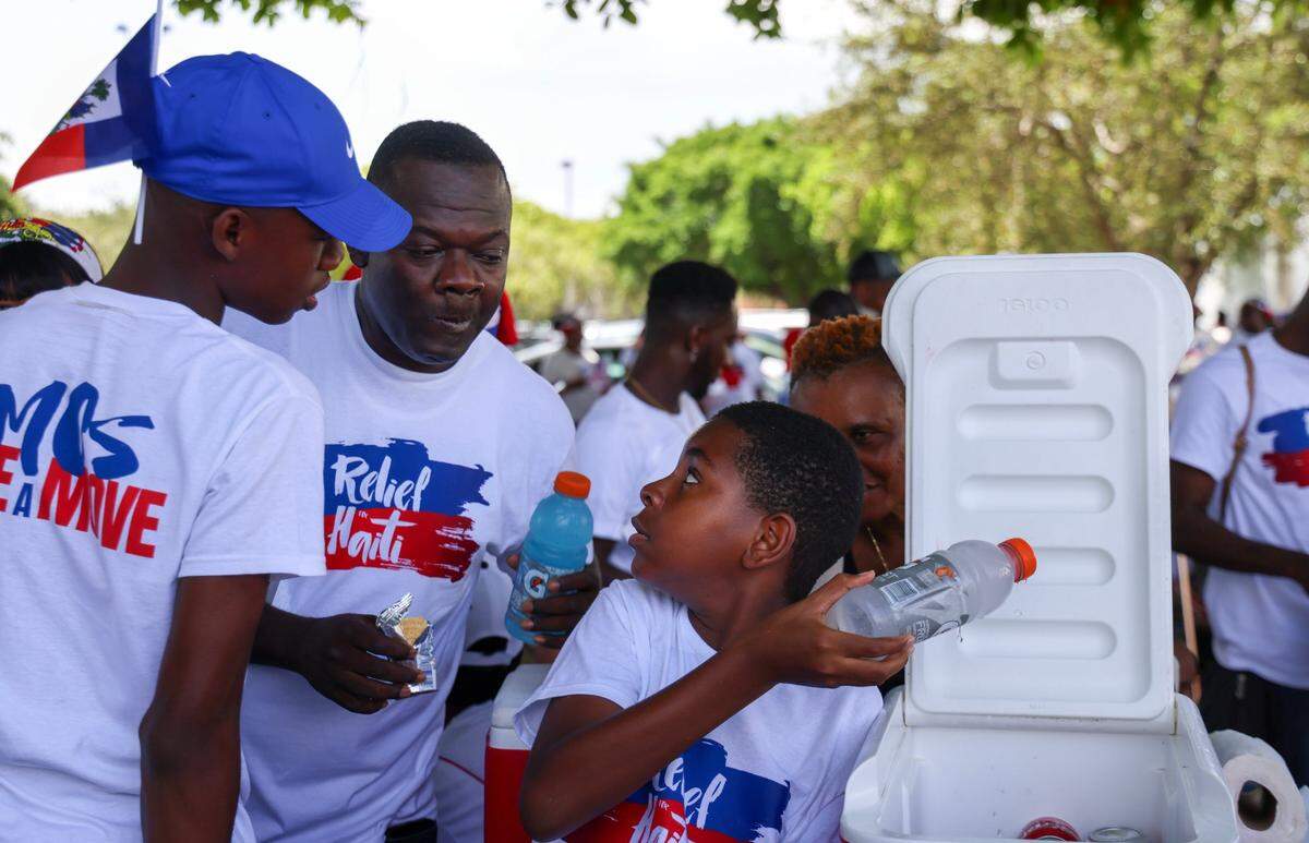 Denzel Sanon, 13, left, and friend Jaivon Rameau, 11, right, sell cold water, sodas, juices and Gatorade to thirsty marchers. About 3,500 North Miami residents and members of the South Florida Haitian community joined Haitians across the U.S. and the world on Sunday, July 9, 2023 to demand relief for Haiti.