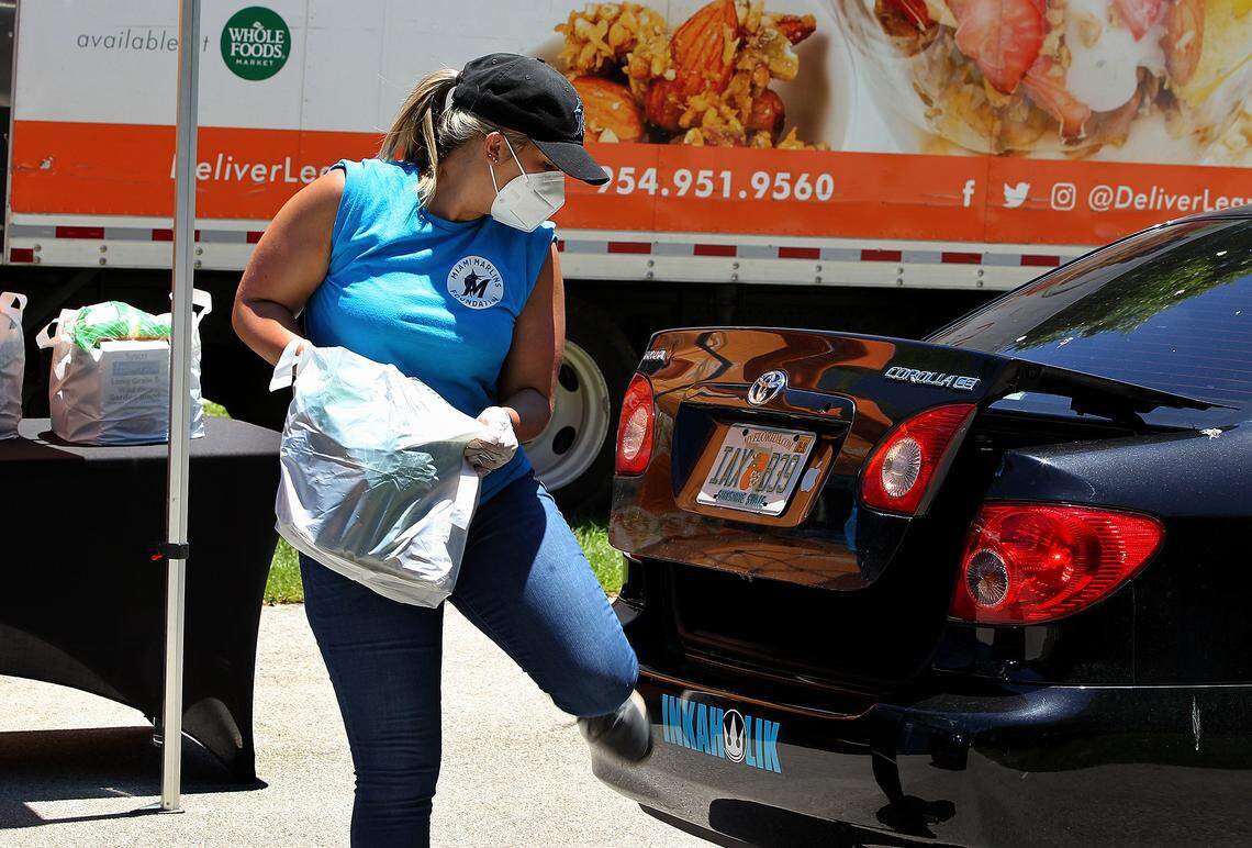 Sarah Garcia, with the Miami Marlins, places a bag of goods in a car’s trunk at a drive-thru only food distribution next to Marlins Park hosted by DeliverLean in partnership with the Miami Marlins Foundation to provide non-perishable items and/or a fresh meal to anyone in need due to the COVID-19 pandemic, on Tuesday, May 05, 2020.