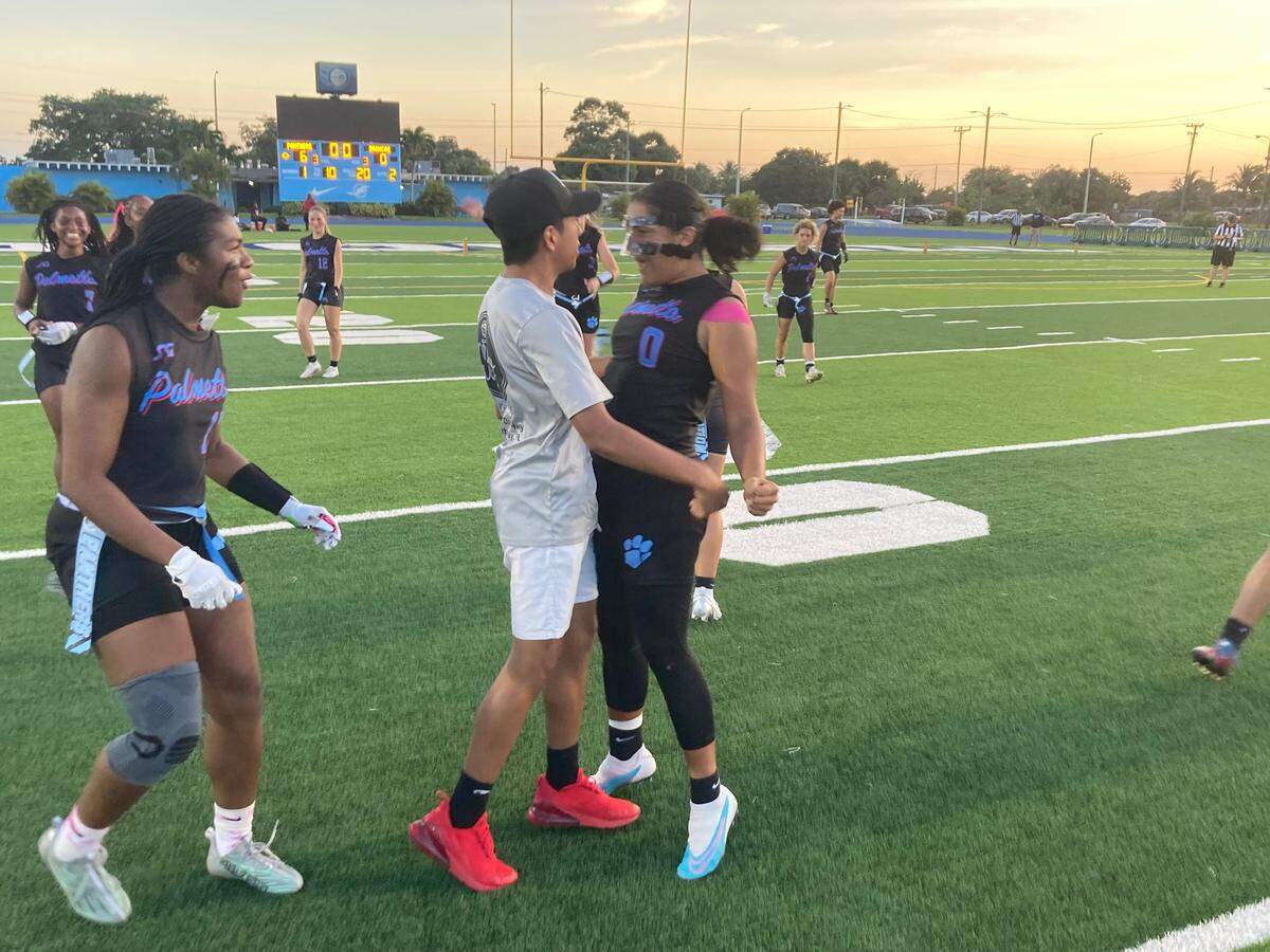 Miami Palmetto’s Ashley Alvarado celebrates her interception return for a touchdown with one of her coaches during the GMAC flag football championship on Friday night at Traz Powell Stadium in Miami, Fla.