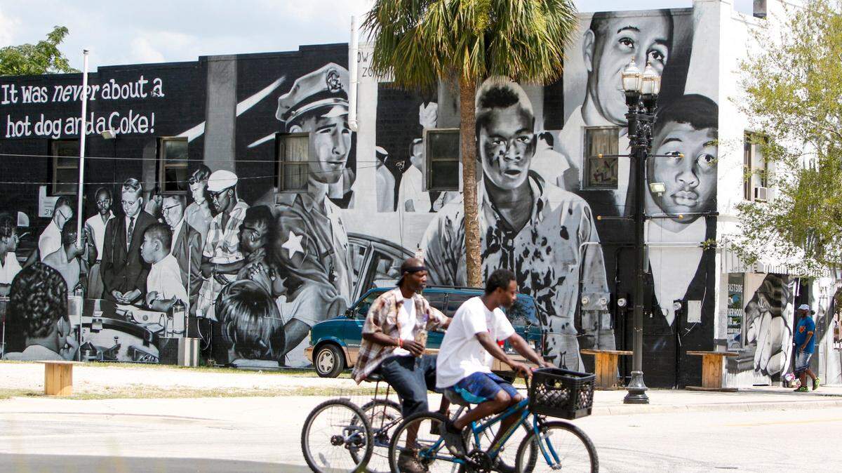 People bike past a mural on the Eastside Brotherhood Club building that depicts “Ax Handle Saturday” on Thursday, June 18, 2020, in Jacksonville. The Republican National Convention is scheduled to happen on the 60th anniversary of the day that the painting refers to, when Black teenagers were met with violence for sitting at a then-segregated lunch counter.



