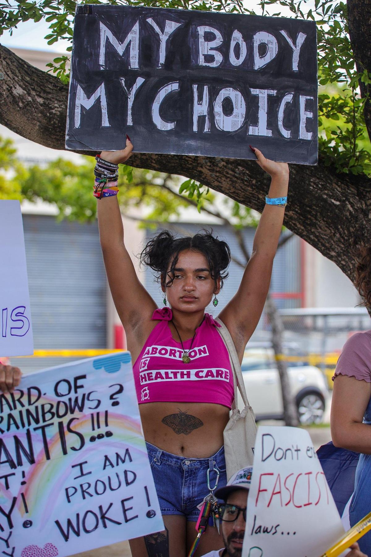 Nathalie Saladrigas, 20, protests against Gov. Ron DeSantis as people gathered outside Metro-Dade Firefighters Local 1403 in Doral, Florida, where DeSantis spoke at a campaign event in support of school board candidates he endorsed.