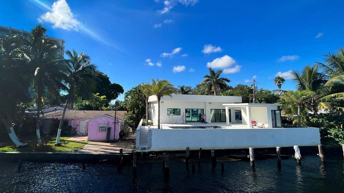 Two next-door homes along the Miami River show the impact of new building and elevation standards compared to older stock housing. Both homes are only one story, but the newer house appears nearly twice as tall as the older one.