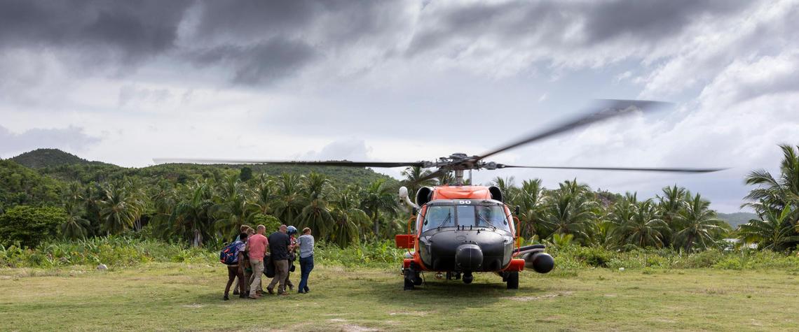 Volunteers in Corail, Haiti, approach a U.S. Coast Guard helicopter with an injured person for evacuation to Port-au-Prince for medical treatment. The small hospital in this small village simply was not equipped to handle certain types of injuries after the earthquake on Aug. 14, 2021.