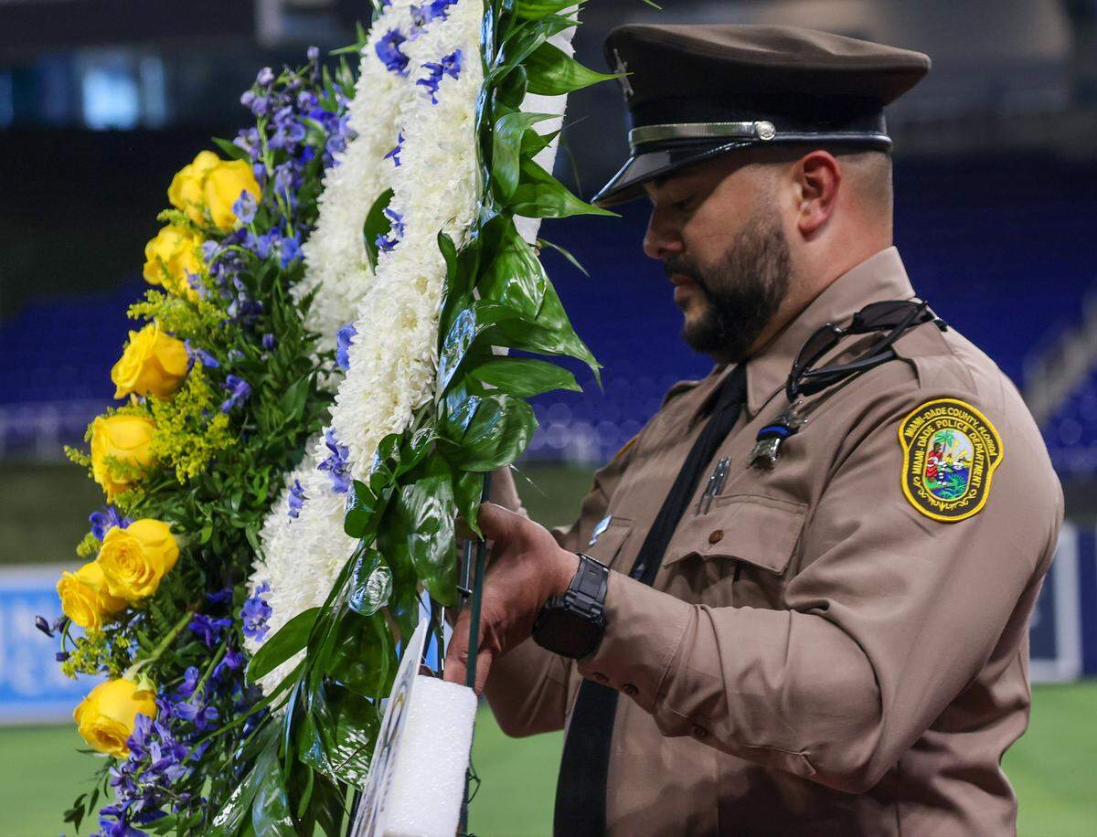 Fellow Miami-Dade deputy sheriff carries a wreath of flowers in preparation of the funeral service for Miami-Dade Deputy Sheriff Devin Jaramillo at Loan Deport Park, where multi-agency officers, public servants, friends, and family members gathered to honor the fallen deputy on Tuesday, November 18, 2025, in Miami, Florida.