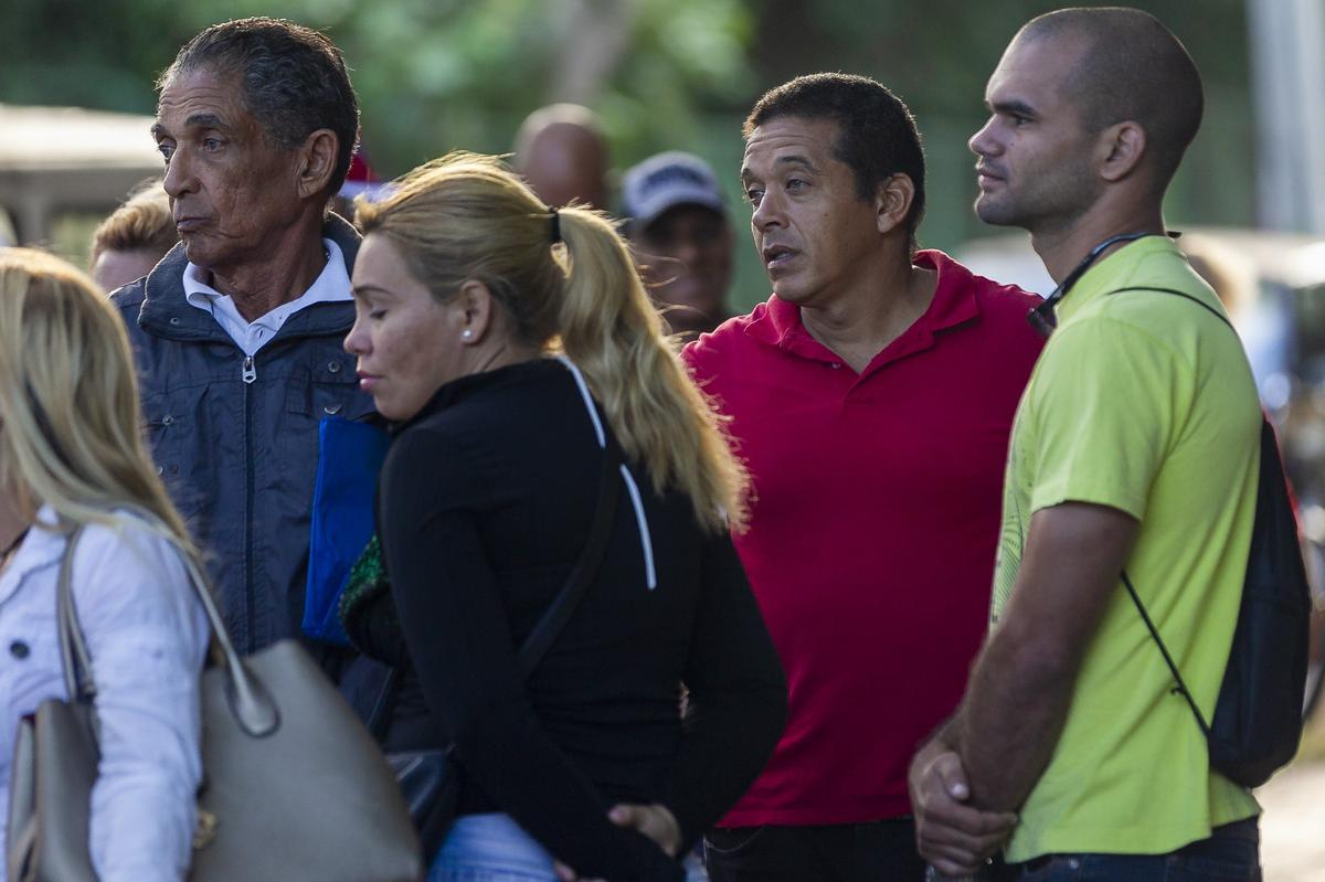 Armando Silvera Rodriguez, center, and his business associate, Elieser Padron Arcia, right, wait outside of the Panamanian Consulate in Havana to get information about a tourist card that would allow them to buy spare parts and equipment for their office machinery repair and maintenance business.
