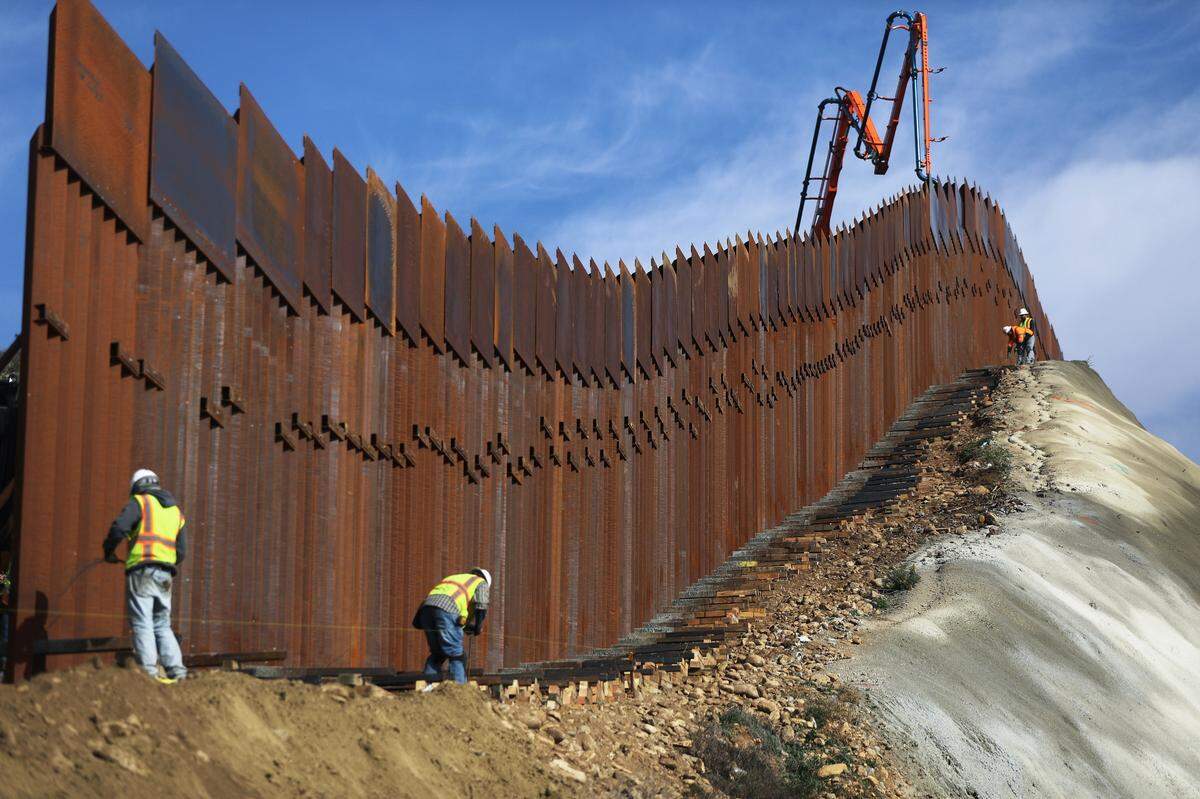 A construction crew works as new sections of the U.S.-Mexico border barrier are installed on January 11, 2019 as seen from Tijuana, Mexico. President Donald Trump is holding off from a threatened national emergency declaration to fund a border wall amid the partial government shutdown.