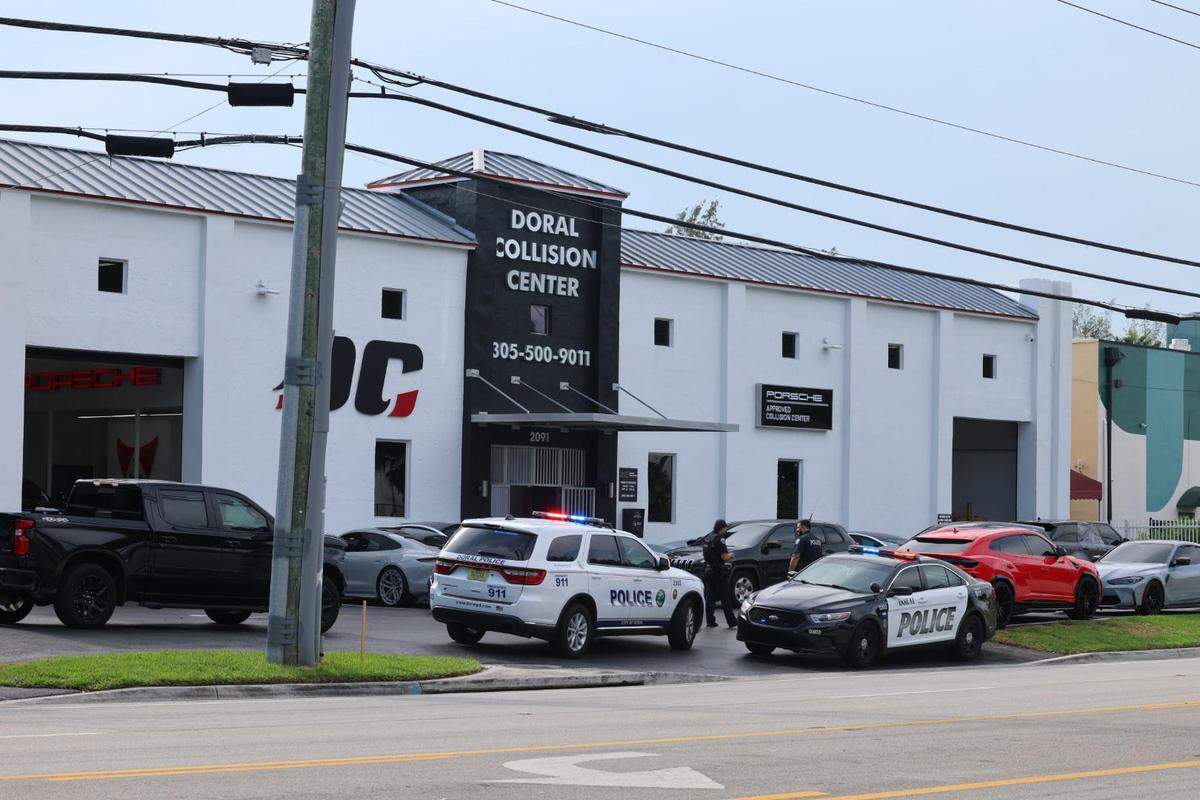 Police and federal agents gather outside Doral Collision Center Friday, Aug. 16, 2024.