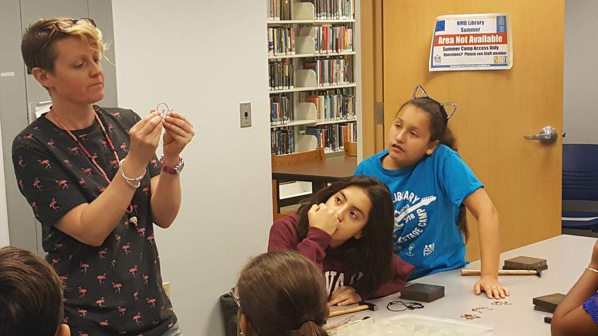 Jewelry Creations Workshop studio manager Tracey Carswell shows a technique to Dezyree de la Huerta and Hannah Hernandez at the latest Young Metal Artist class July 3 at North Miami Beach Library.